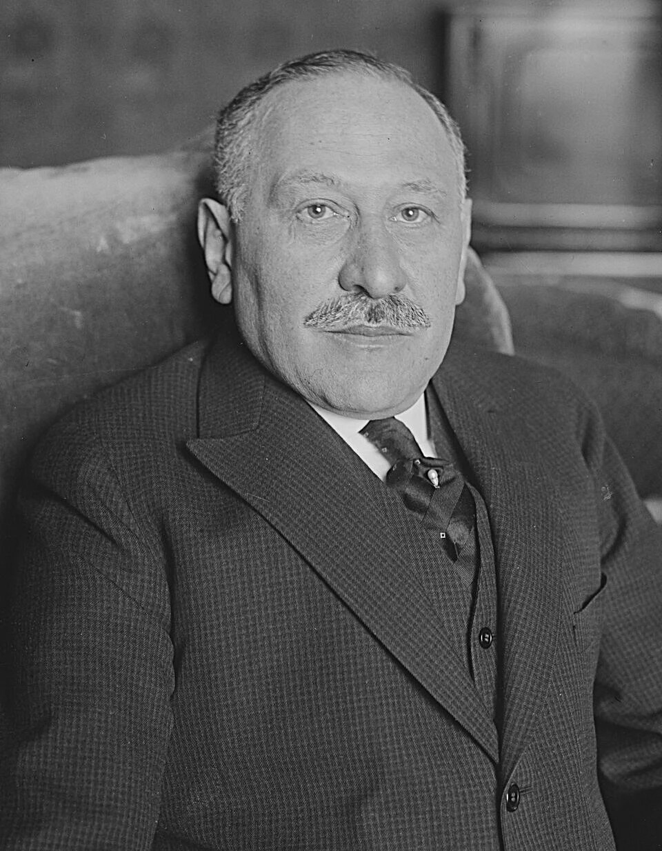 Black and white portrait of Julius Rosenwald. He is depicted sitting in a chair wearing a dark suit coat, dark tie, and a white shirt.